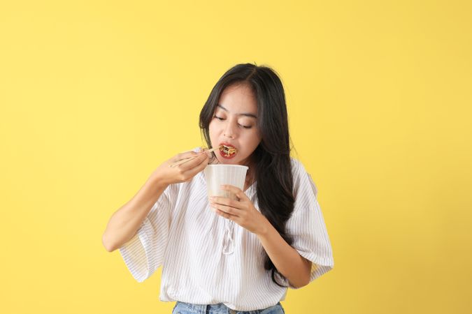 Girl using Chopsticks Eating Instant Ramen, Noodles Soup from a Cup