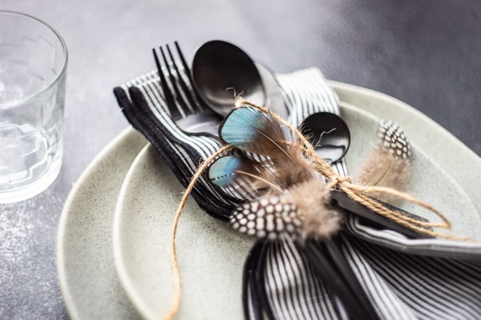 Table setting with decorative feathers on concrete background