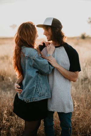 Hipster couple bonding on field in sunlight