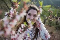 Young happy woman between trees in garden