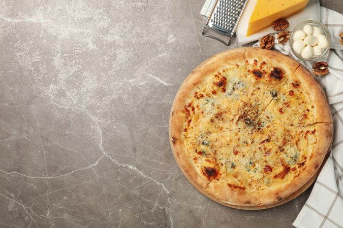Cheese pizza and ingredients for cooking on gray background
