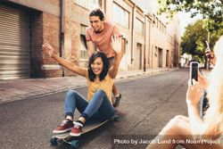 Two people having fun on skateboard with friends taking their pictures 0Pva74