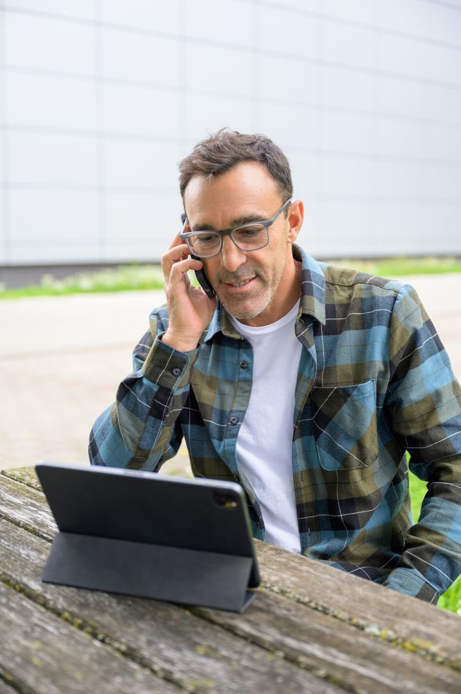 Smiling man talking on phone and using laptop