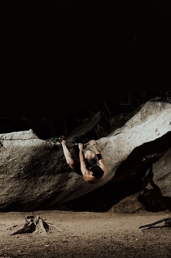 Man practicing rock climbing among large rocks in a forest
