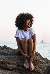 Delighted Black woman laughing at seaside