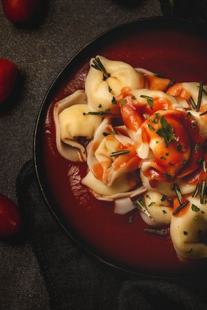 Plate of delicious ravioli with tomato sauce served on table