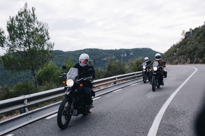 Group of bikers on mountainous highway, riding on curve road pass across Alpine mountains