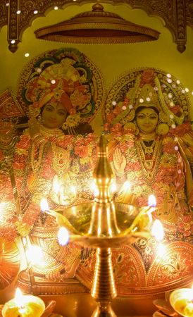 Lit pancha aarti beside two Hindu deities