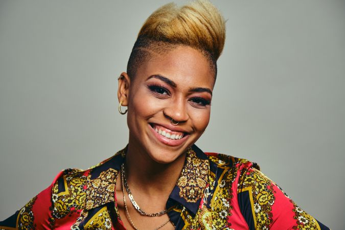 Portrait of joyful Black woman with short blonde hair in bold patterned shirt
