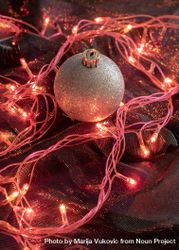 Metallic holiday ornament on red cloth with fairy lights 0vZqg0