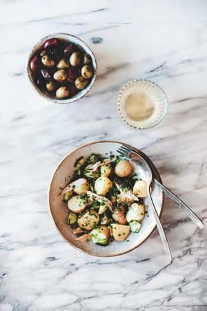 Greek style potato salad, olive bowl and wine, top view