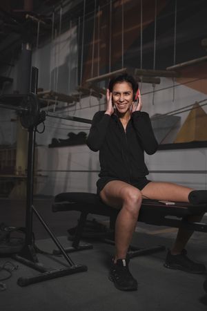Woman with headphones and device sitting in gym
