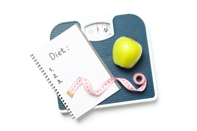 Scales, measuring tape, apple and copybook isolated on blank background