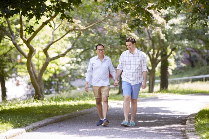Two men holding hands and walking between trees