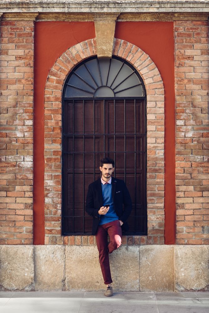 Smartly dressed man standing outside ornate arch outside
