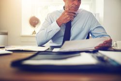 Man in business attire looking over documents at desk