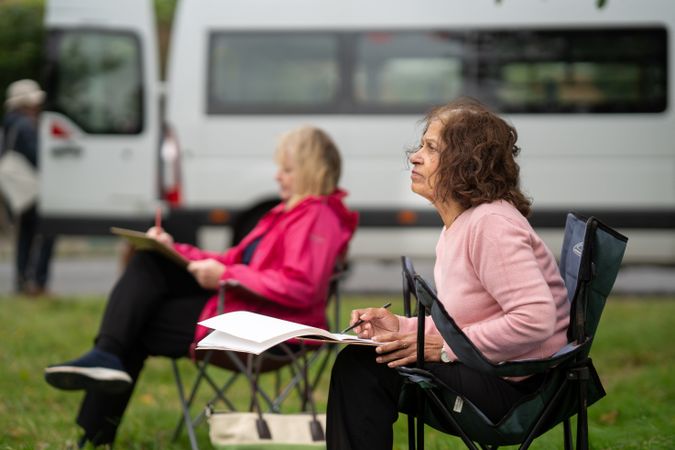 Side view of two woman sitting and drawing