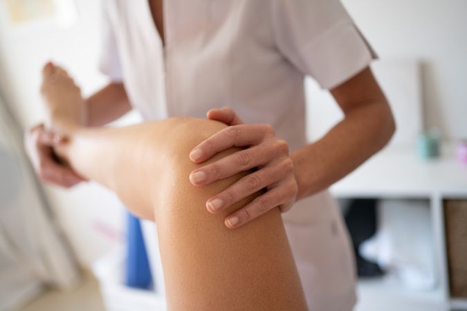 Professional physiotherapist treating knee of patient