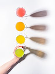 Hand and glasses of bright colorful drinks on table
