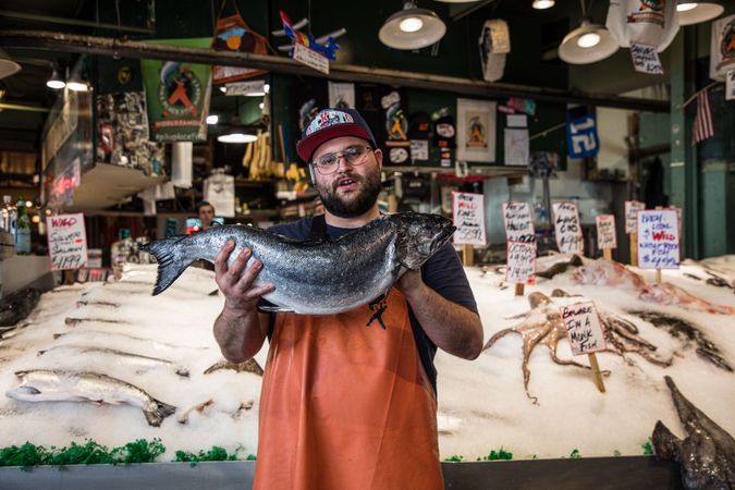 A fishmonger displays catch of the day at Pike Place Market, Seattle, Washington