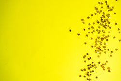 Festive xmas card concept of star glitter on yellow background