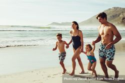 Cheerful family running on the beach 0WGA60