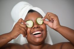 Black woman with cucumber slices on eyes