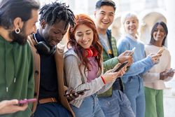 Students standing around campus checking their phones