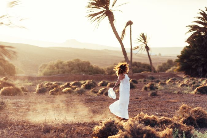 Woman in white dress in dry field in sunlight