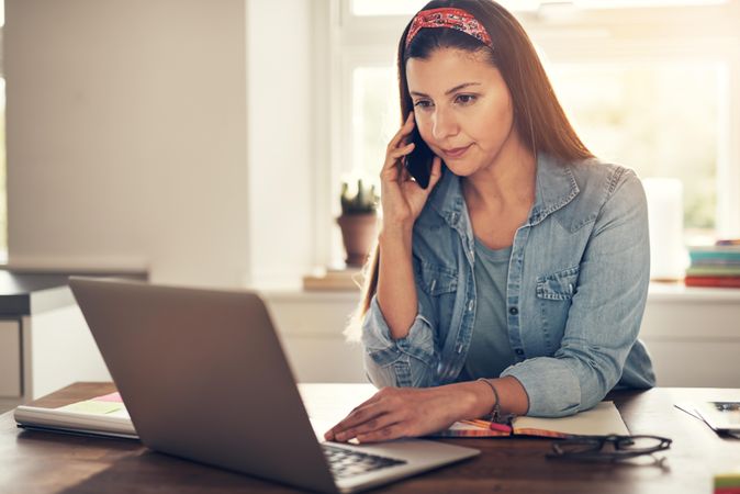 Woman reading something on laptop while taking a phone call