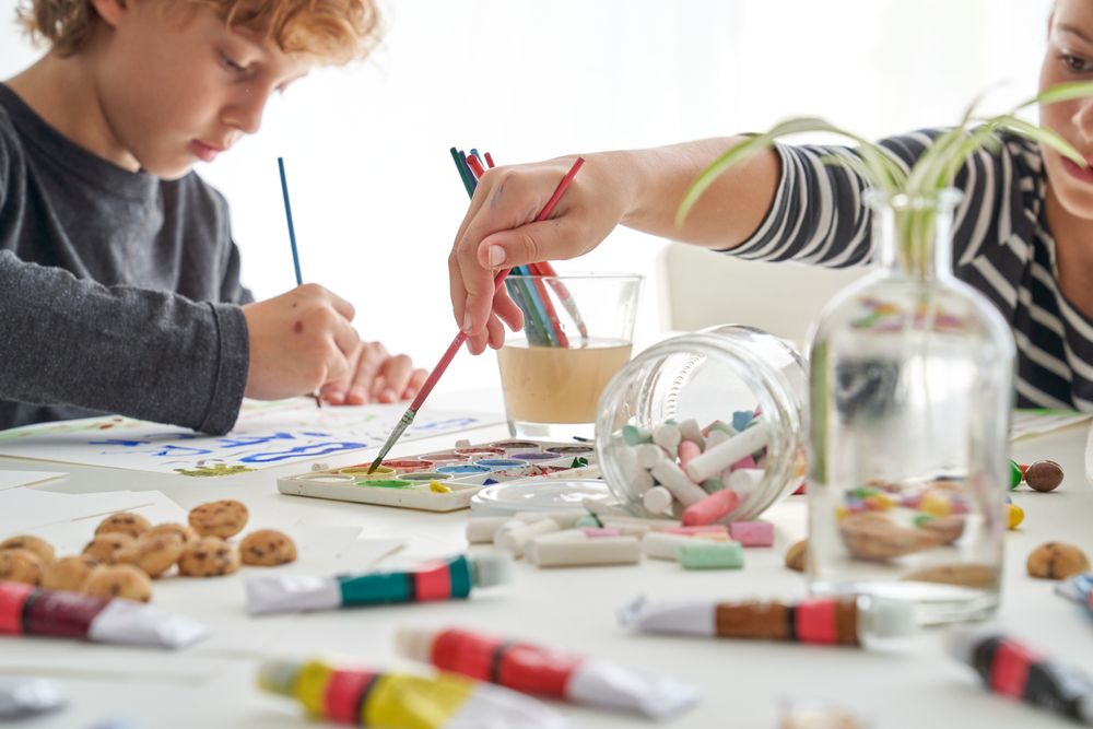Children painting with paints at table