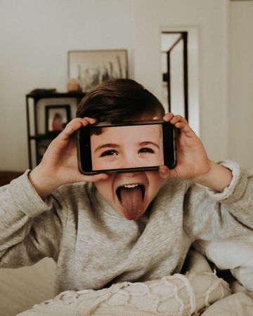 Child holding mobile phone over eyes