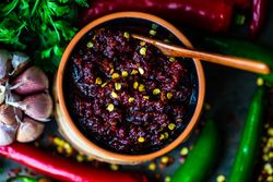 Close up of pot of traditional Georgian sauce Adjika with garlic bulb & raw ingredient