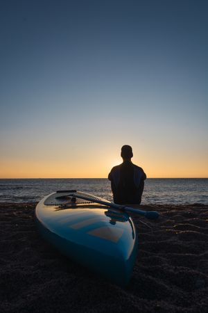 Man practicing paddle surfing with neoprene in a sunrise