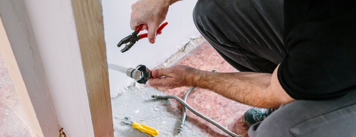 Plumber doing heating installation on a construction site