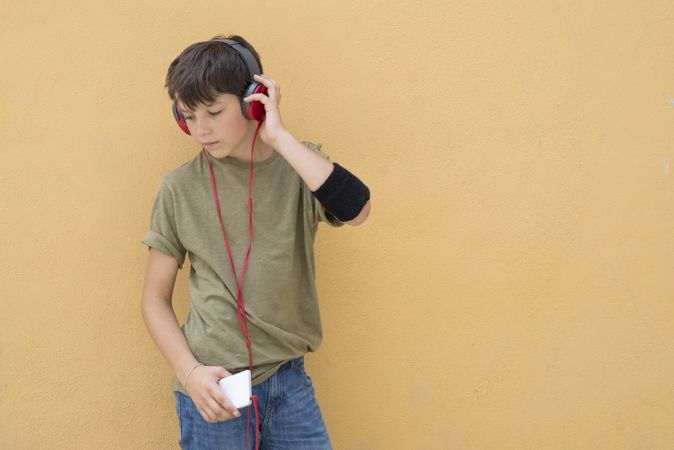 Handsome teen wearing a green T-shirt listening to music