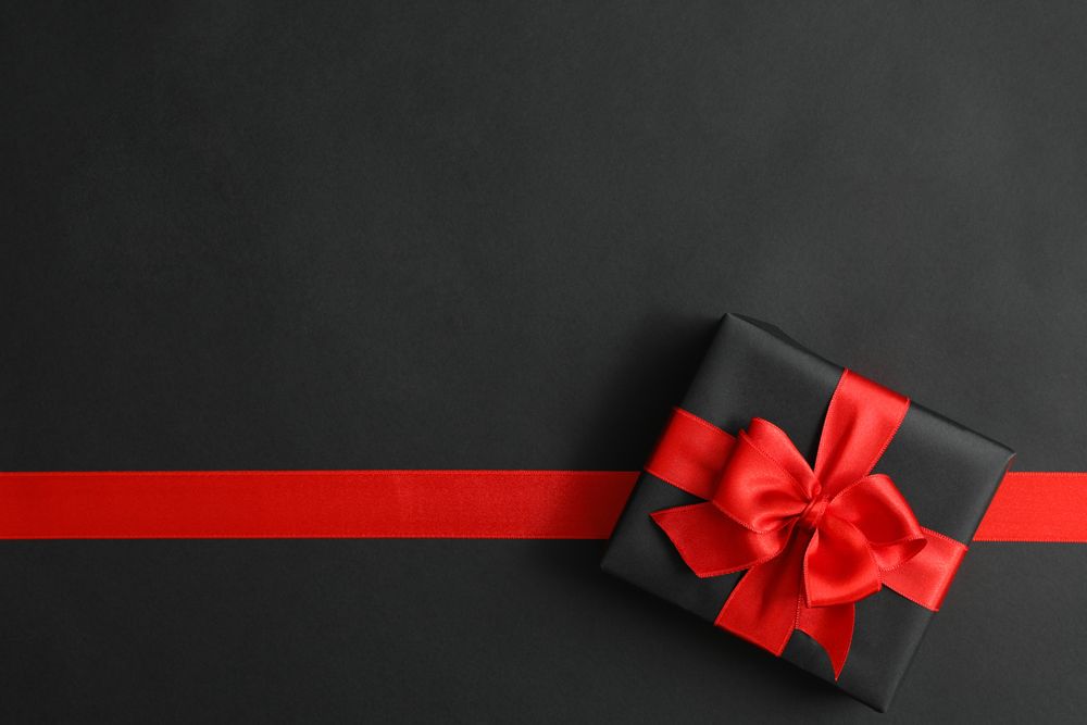 Gift box and red ribbon on dark background