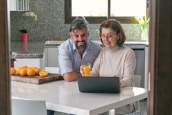 Mother and son smiling and browsing netbook together in kitchen