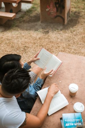 Top view of man and woman reading books sitting outdoor