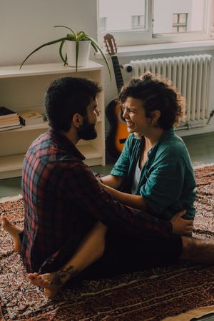 Loving couple embracing while sitting on apartment floor