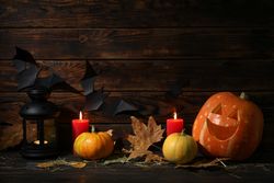 Halloween pumpkins and candles on dark wooden background, copy space
