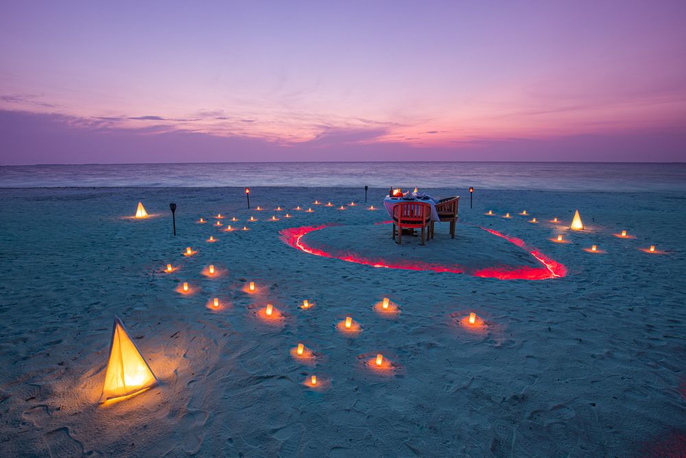 Beautiful dinner setting on a beach with candles at dusk