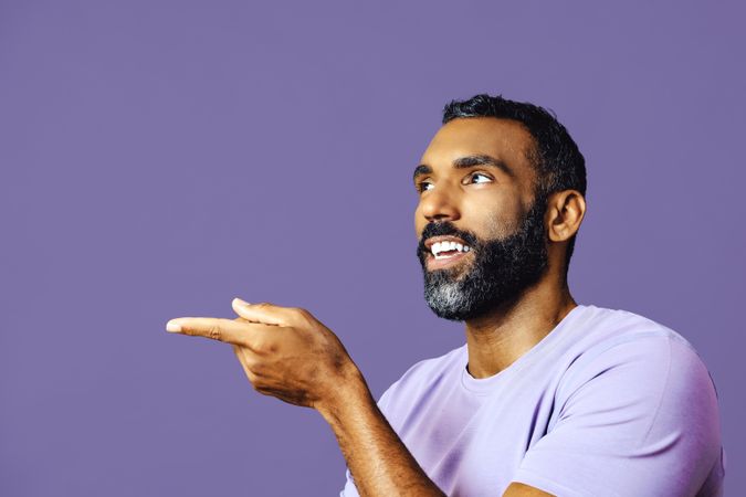 Side view of male talking in purple t-shirt while gesturing to the side, copy space