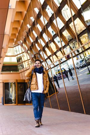 Stylish guy using smartphone outside modern building