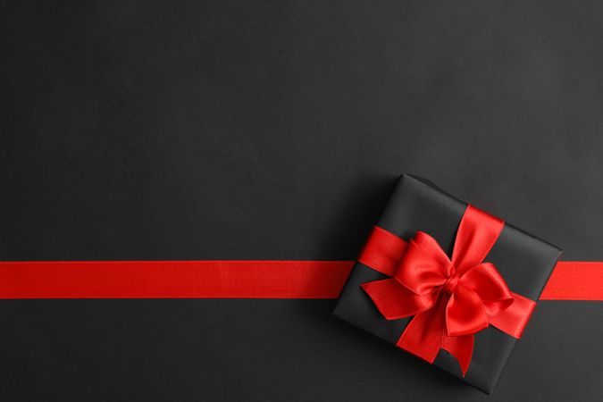 Gift box and red ribbon on dark background