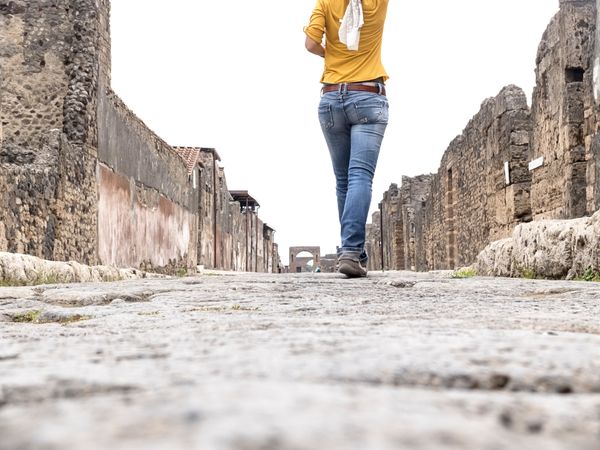 Low angle view of a woman in yellow clothes walking while exploring ancient ruins
