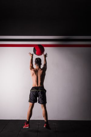 Man throwing ball on wall in gym