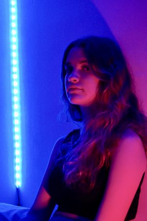 Side view of teenage girl in purple lit studio