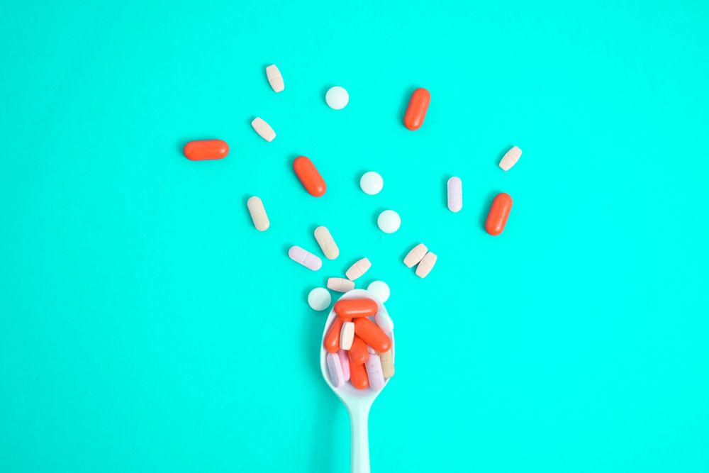 Spoon with scattered colorful tablets