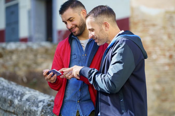 Cute gay couple smiling at something over a phone